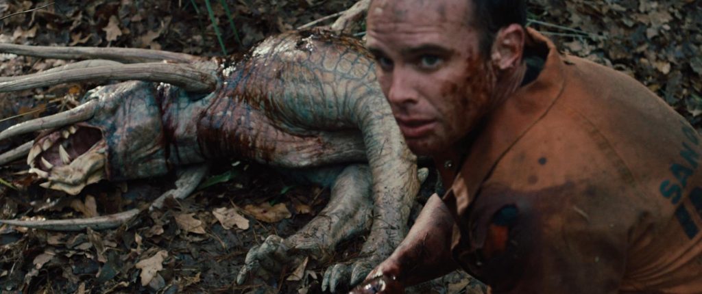 A bloody Walton Goggins in front of a fresh predator hound corpse as seen in Predators 2010.