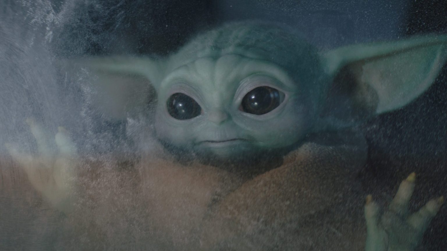 Baby Yoda looking outside of a frozen window as seen in Chapter 10 of The Mandalorian.
