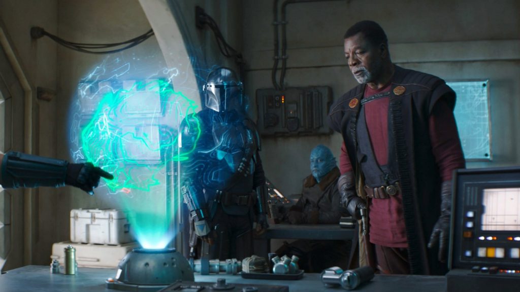 Carl Weathers as Greef Karga inspects a holographic map with Pedro Pascal's title character as seen in Chapter 12 of The Mandalorian.