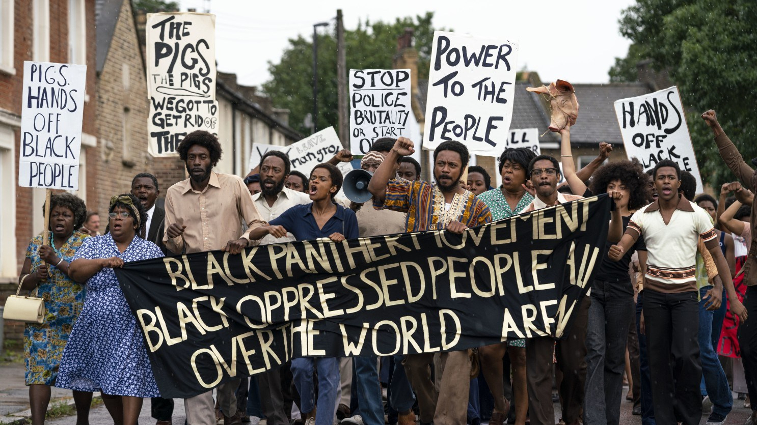 The Mangrove protests march down the street with signs and banners denouncing police brutality as seen in Steve McQueen's Small Axe Anthology. 