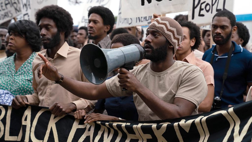 Malachi Kirby leads the Mangrove protests with a megaphone as seen in Steve McQueen's Small Axe anthology.
