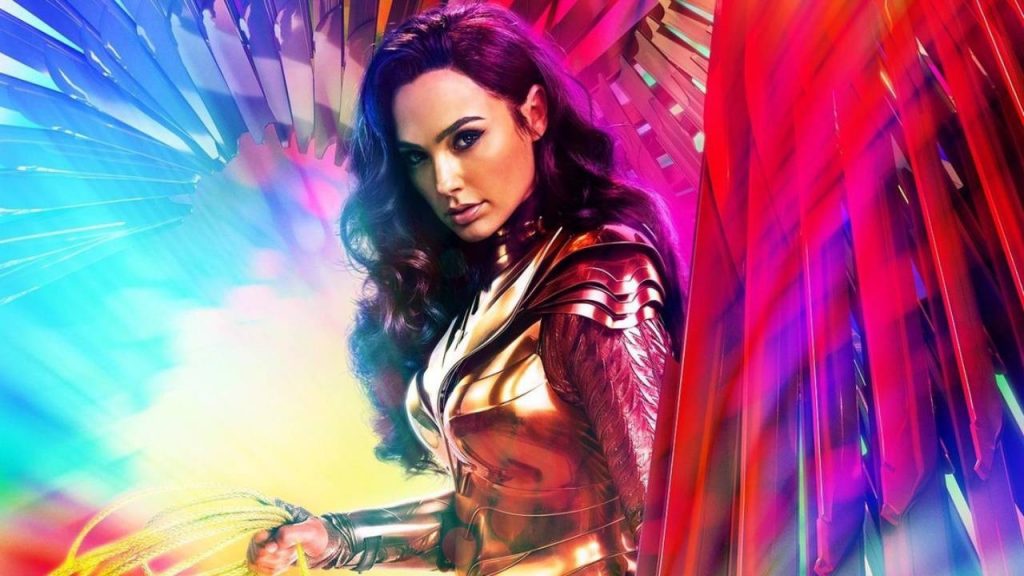 Gal Gadot looking stunning in golden armor around colorful promotion for Wonder Woman 1984.