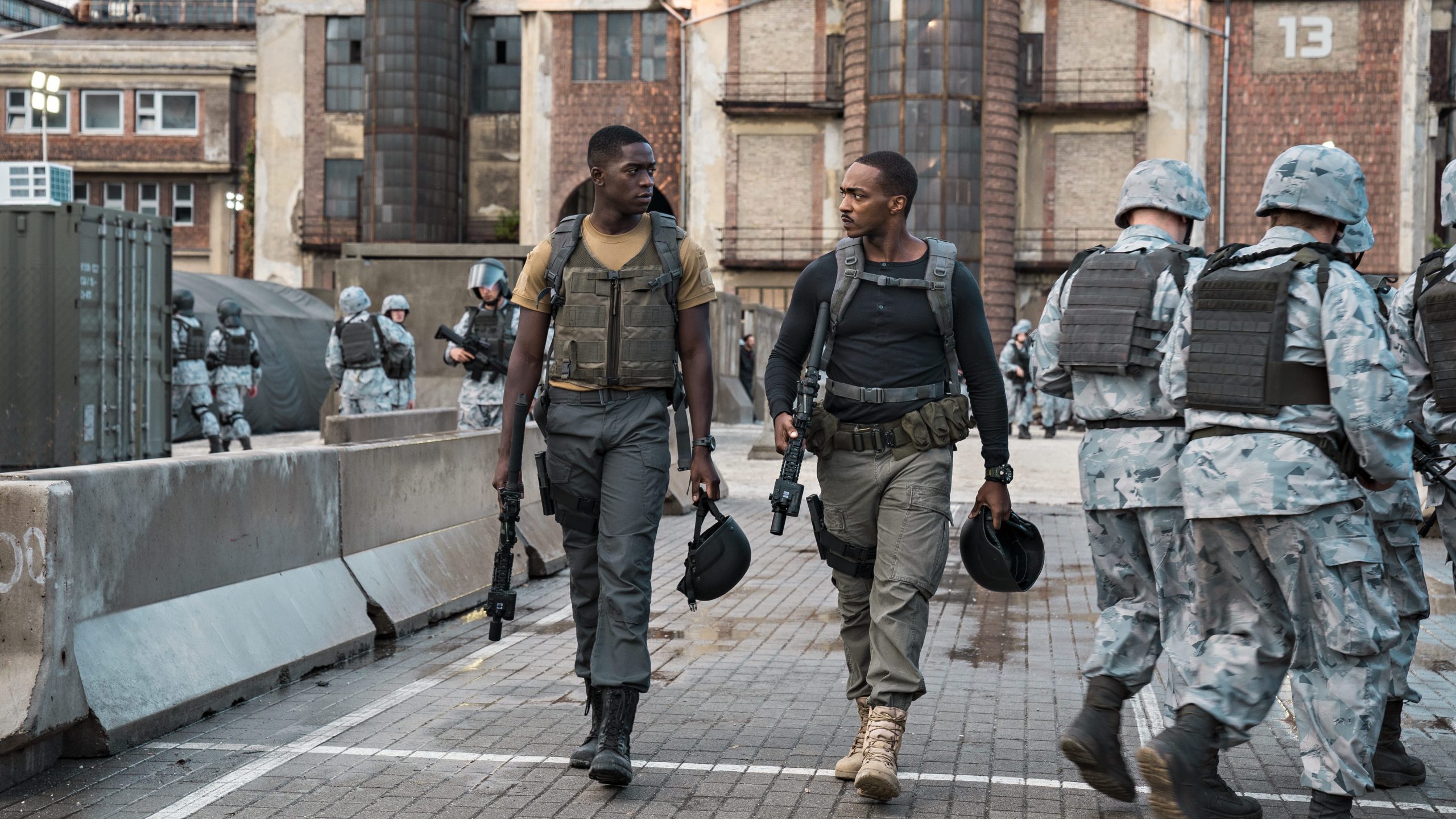 Damson Idris and Anthony Mackie walk alongside U.S soldiers in a futuristic base as seen in Outside the Wire. 
