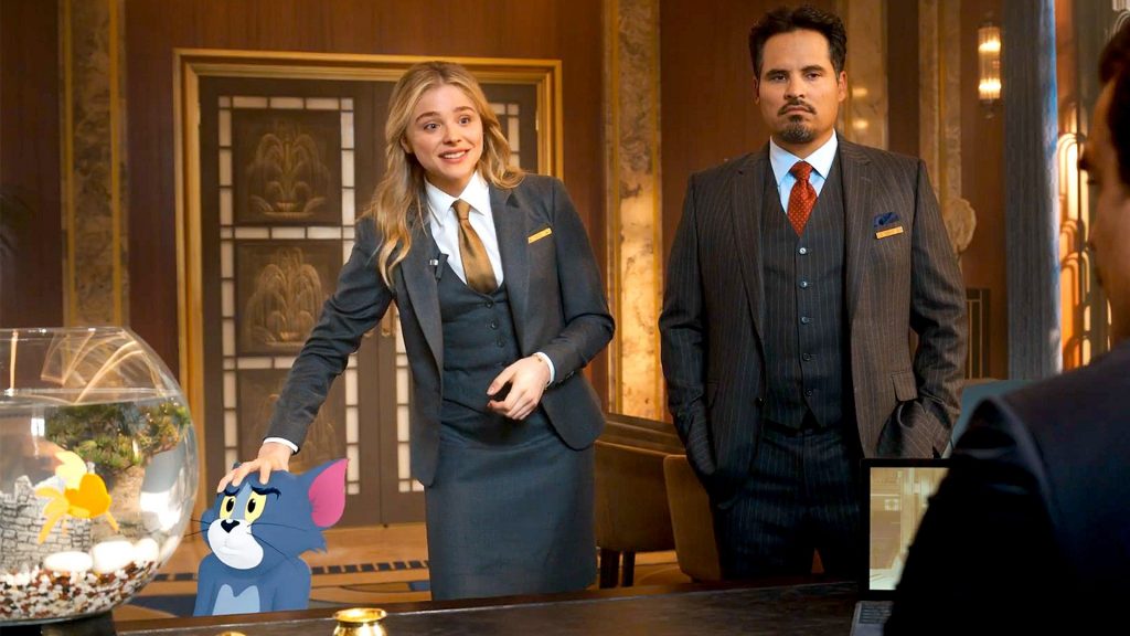 Chloë Grace Moretz and Michael Peña in a hotel's manager office with an animated Tom as seen in the 2021 film Tom & Jerry.