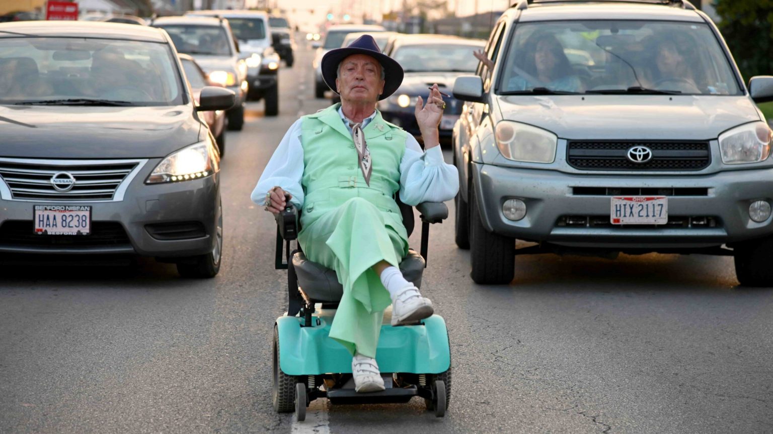 Udo Kier wearing a colorful suit while driving a wheel chair as seen in the SXSW film Swan Song.