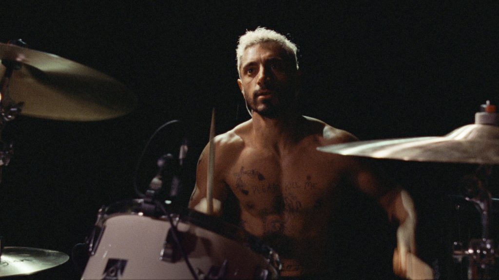Riz Ahmed playing drums shirtless as seen in the Oscar nominated film Sound of Metal. 