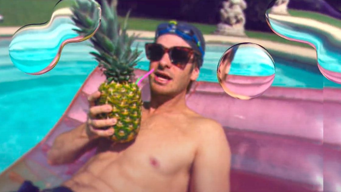 Andrew Garfield sipping out of a pineapple on a pool with a social media bubble filter as seen in Mainstream directed by Gia Coppola. 