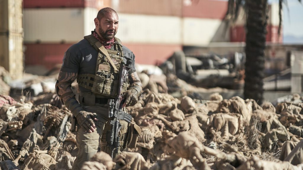 Dave Bautista in a mercenary uniform standing in a sea of zombie corpses as seen in the new Netflix film Army of the Dead directed by Zack Snyder.