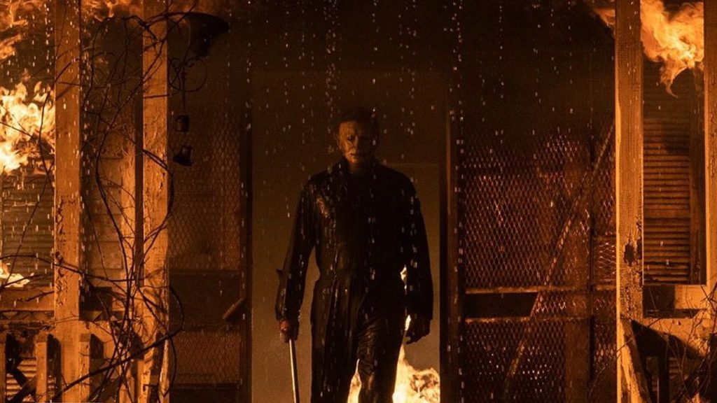 Michael Myers steps out of a burning house with a huge metal blade ready in hand as seen in HALLOWEEN KILLS produced by JASON BLUM. 