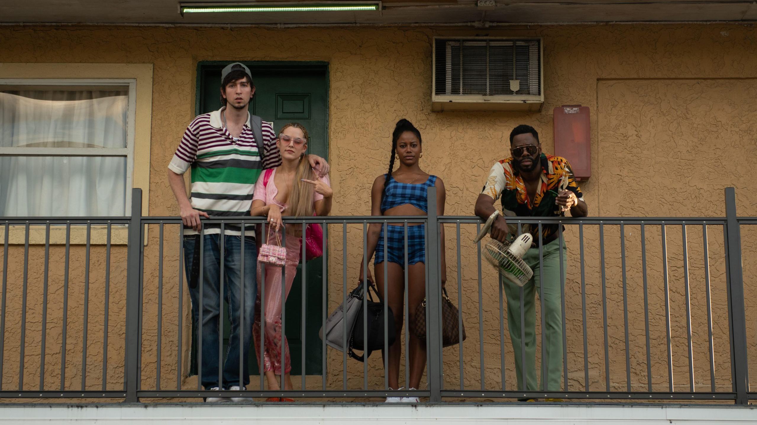 Nicholas Braun, Riley Keough, Taylour Paige, and Colman Domingo hanging out together on a balcony as seen in the latest A24 film ZOLA. 