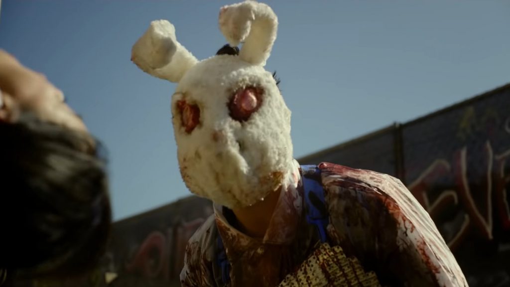 A purger wearing a bloody bunny mask looks over a helpless person in his trap as seen in the new Horror sequel THE FOREVER PURGE.