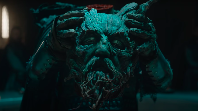 The Green Knight himself, a being made out of tree bark and roots, holds his own decapitated head inside Camelot as seen in the new A24 film THE GREEN KNIGHT directed by David Lowery. 