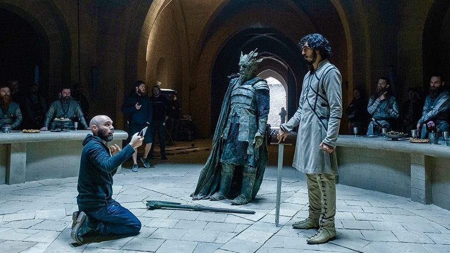 Director David Lowery stages a scene with Ralph Ineson in full Green Knight costume and makeup and Dav Patel as Sir Gawain on the set of the latest A24 film.