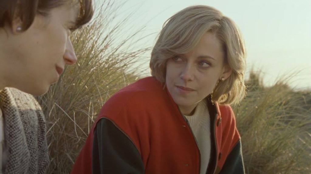 Kristen Stewart as Princess Diana sits in a field with a friend as seen in SPENCER directed by Pablo Larraín. 