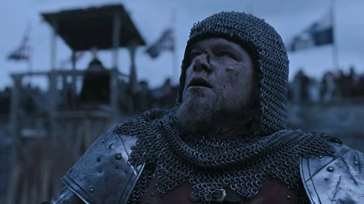 Matt Damon as Jean de Carrouges bloodied and looking defeated in knight's armor as seen in THE LAST DUEL directed by Ridley Scott.
