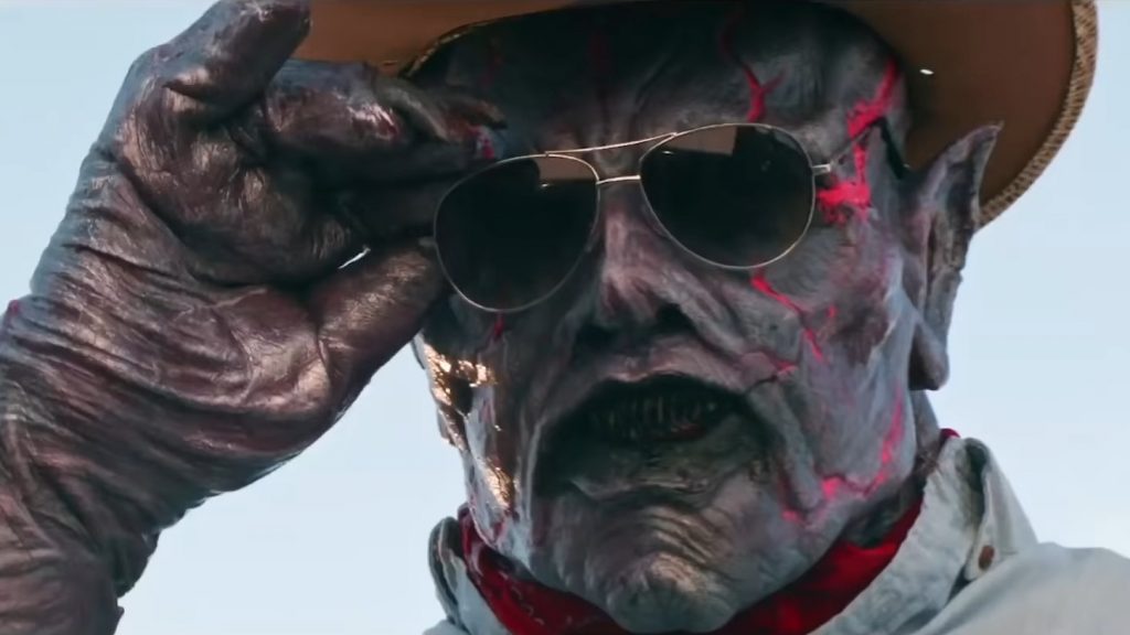Psycho Goreman wearing a cowboy hat and red bandanna takes off his sunglasses in style as seen in PSYCHO GOREMAN - one of our top 10 best horror films of the year so far.  
