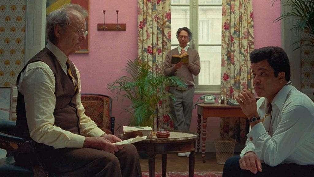 Bill Murray, Wally Wolodarsky, and Jeffrey Wright have a meeting in a fancy colorful room as seen in THE FRENCH DISPATCH directed by Wes Anderson.