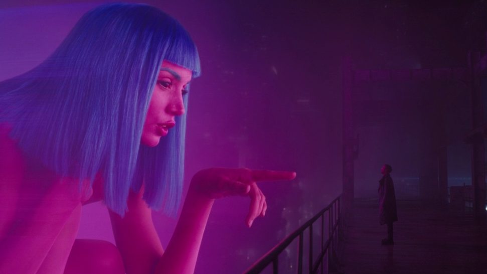 Ana de Armas as a giant naked Joi hologram points down at a saddened K played by Ryan Gosling in BLADE RUNNER 2049 directed by Denis Villeneuve. 