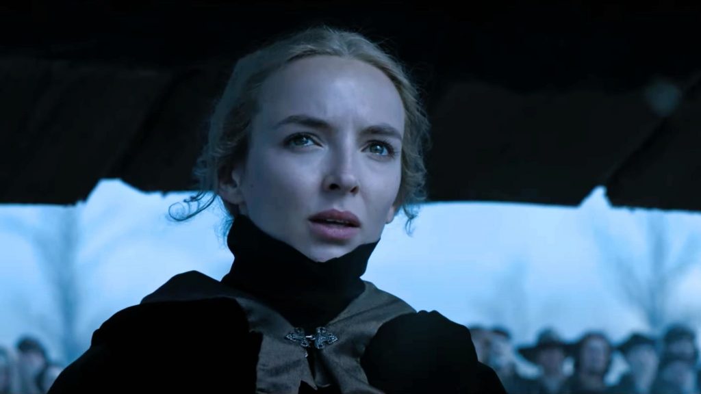Jodie Comer slowly sheds a tear as she watches her husband and abuser battle it out under a blue gray sky in THE LAST DUEL directed by Ridley Scott.