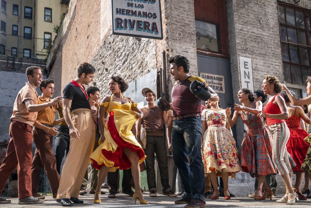 Ariana DeBose as Anita and David Alvarez as Bernardo are the center of attention in a Puerto Rican crowd in WEST SIDE STORY directed by Steven Spielberg, which features no subtitles for scenes in Spanish.