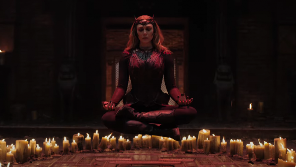 Wanda Maximoff meditates and levitates around burning candles in her new Scarlet Witch costume in the 2022 film DOCTOR STRANGE IN THE MULTIVERSE OF MADNESS.