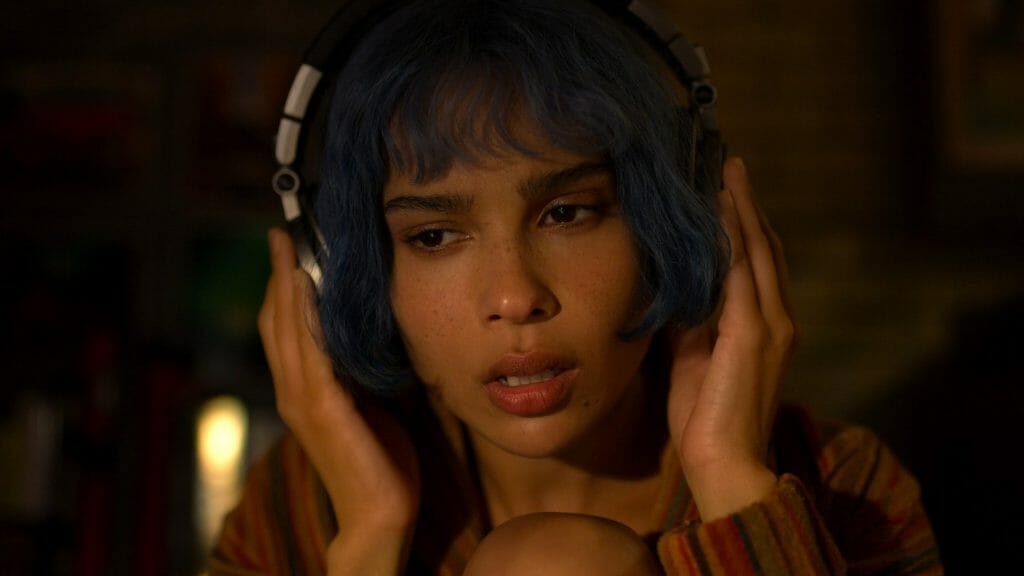 Zoë Kravitz sporting blue short hair and listening closely to her headphones as seen in KIMI directed by Steven Soderbergh, coming to HBO Max in February 2022.