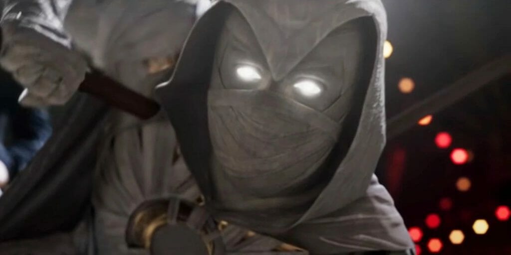 Moon Knight in his signature white costume holds an action pose as he raises his fist for a punch towards the camera in the new MCU series on Disney+.