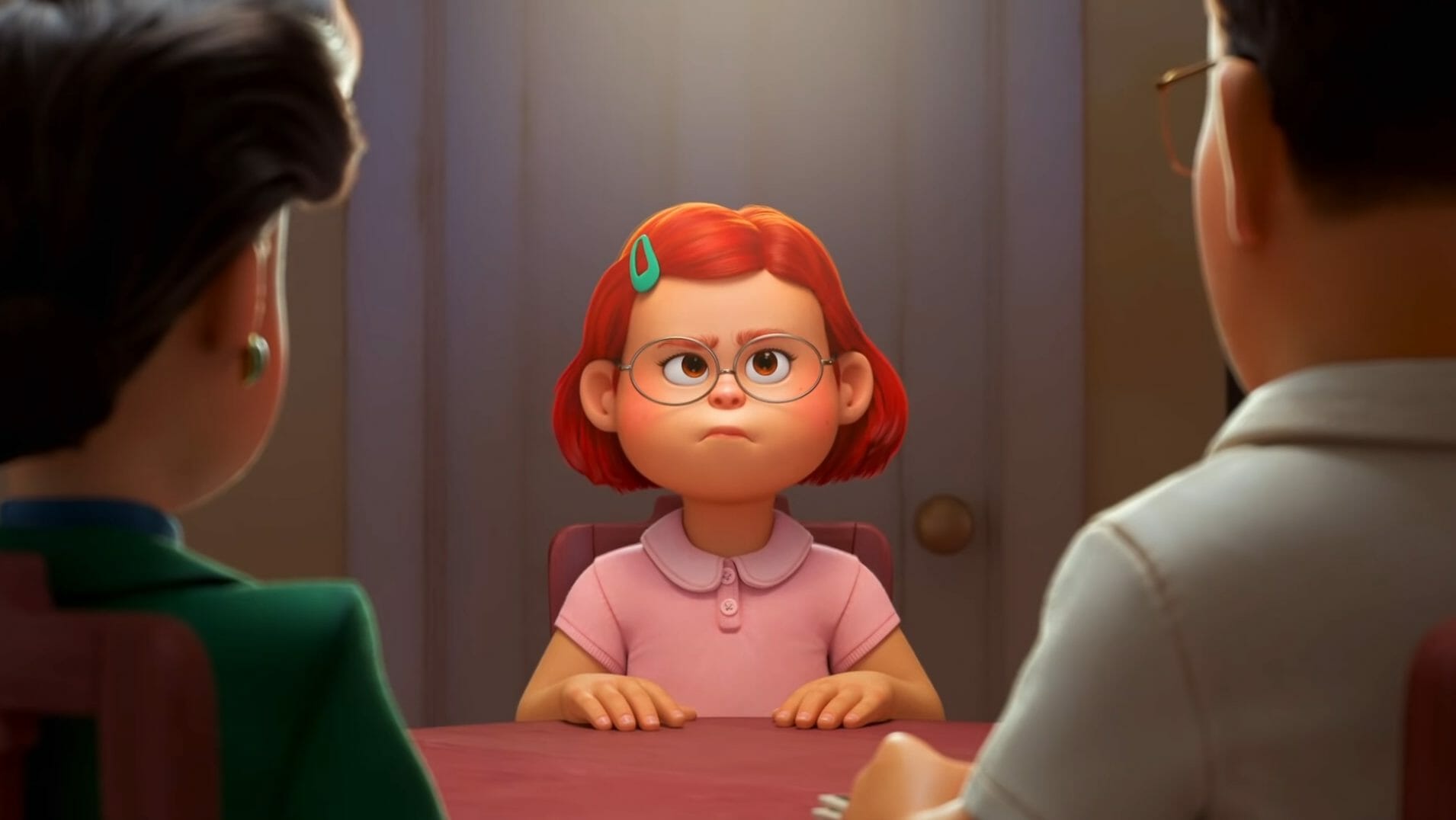 Mei with her new red hair sits between her mom and dad during a serious talk in the new Pixar film streaming on Disney+, TURNING RED.  