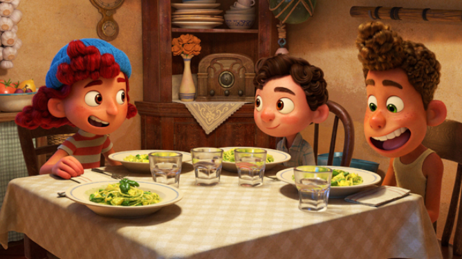 Giulia, Luca, and Alberto sit around the kitchen table with plates of pasta in front of them. 