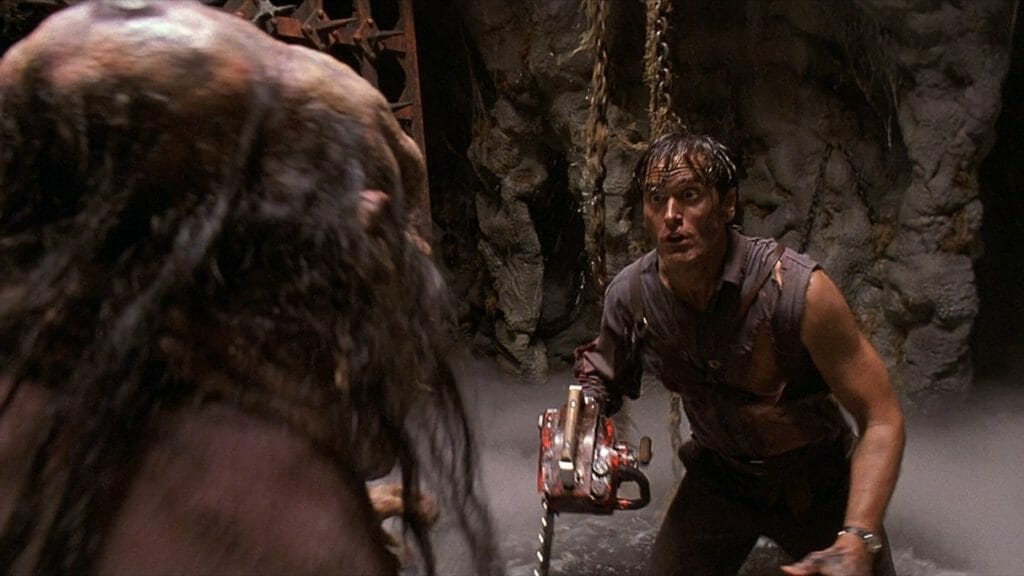 Ash Williams wrestles with a deadite witch at the bottom of water pit with spiked walls closing in as seen in ARMY OF DARKNESS directed by Sam Raimi. 