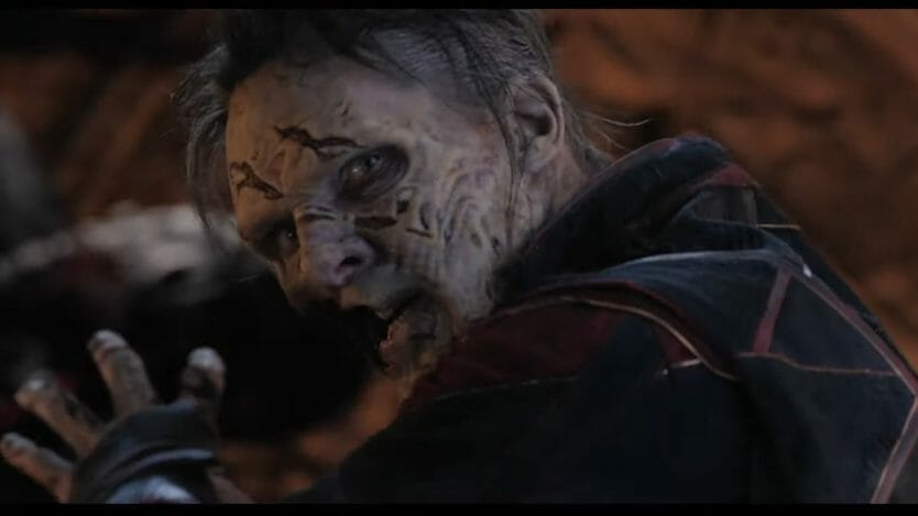 A zombie MCU version of Doctor Strange looks back at the camera as he attempts to hold back the Scarlet Witch with his demons spirit powers in DOCTOR STRANGE IN THE MULTIVERSE OF MADNESS directed by Sam Raimi.