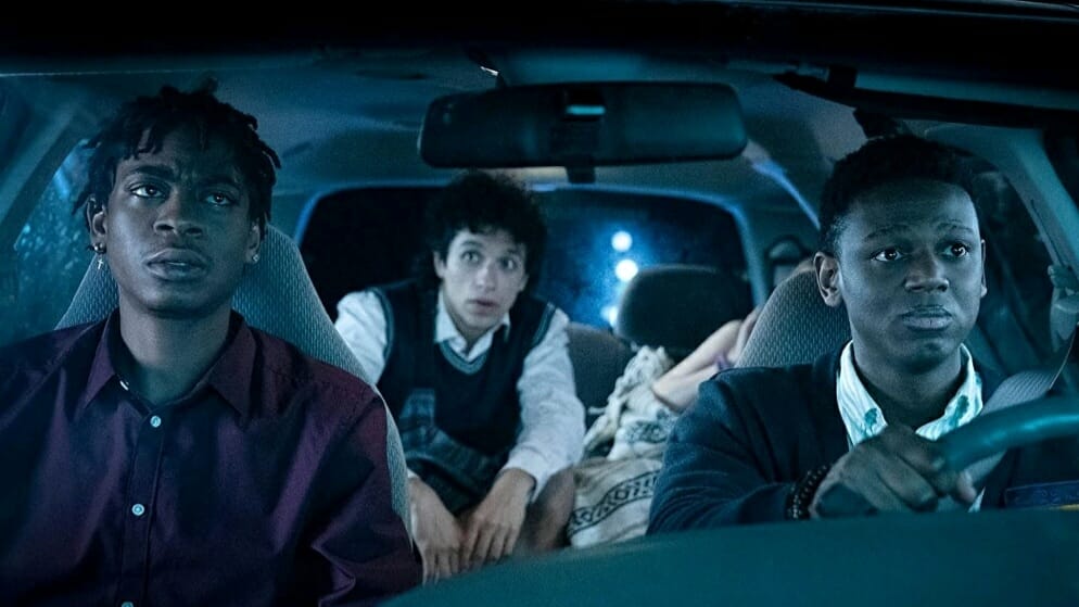Donald Elise Watkins nervously drives RJ Cyler in the passenger seat of a car while Sebastian Chacon and a passed out Sabrina Carpenter sit in the back in the dark college comedy EMERGENCY now streaming on Prime Video.