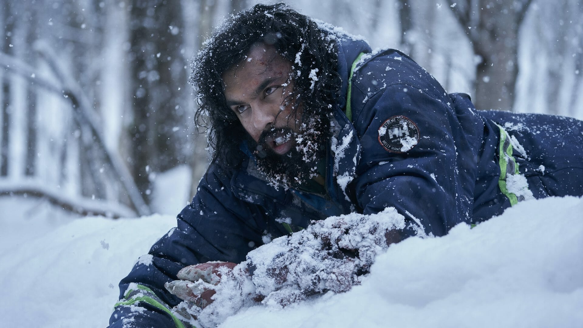 Himesh Patel drags himself across a frozen hill of snow in pain with a broken leg in the HBO Max original limited series STATION ELEVEN. 