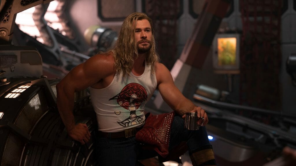 Chris Hemsworth poses with his red leather jacket and long hair with a metal Guns N' Roses inspired shirt in THOR: LOVE AND THUNDER.