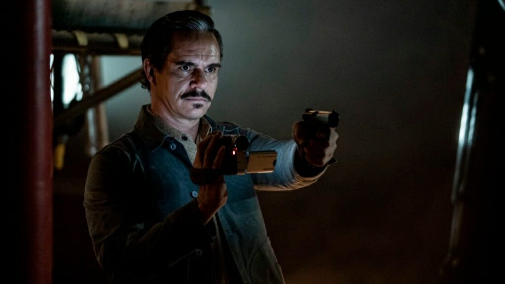 Lalo Salamanca played by Tony Dalton holds a camcorder with one hand and a gun in the other as he prepares to enter his fateful final shoot out before his death in the final season of BETTER CALL SAUL.