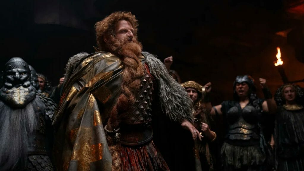 Owain Arthur as the Dwarf prince Durin IV being cheered on by a crowd of fellow Dwarfs in iron armor in THE LORD OF THE RINGS: THE RINGS OF POWER on Amazon Prime Video.