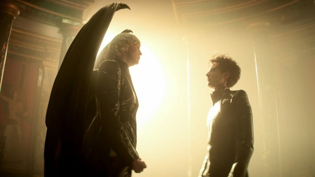 Gwendoline Christie towers over Dream played by Tom Sturridge in Hell with her large pointed black demon wings in THE SANDMAN on Netflix.