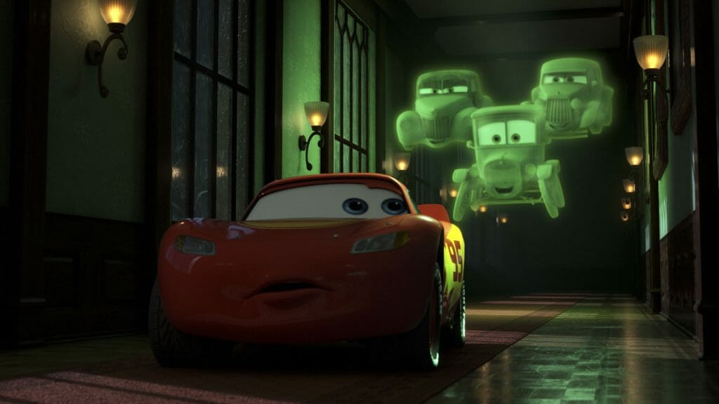 Lightning McQueen is followed by three green floating old car ghosts in a scary haunted mansion corridor in CARS ON THE ROAD on Disney+.  