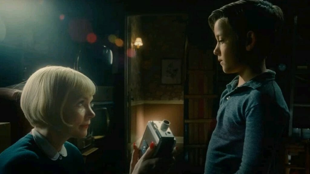 Michelle Williams presents young Sammy Fabelman played by Mateo Zoryon Francis-DeFord with a brand new Super 8 camera in THE FABELMANS directed by Steven Spielberg.