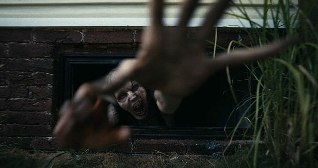 Matthew Patrick Davis stars as the Mother monster in BARBARIAN as she reaches out and screams to the camera from a basement window to grab her baby hostage victim.