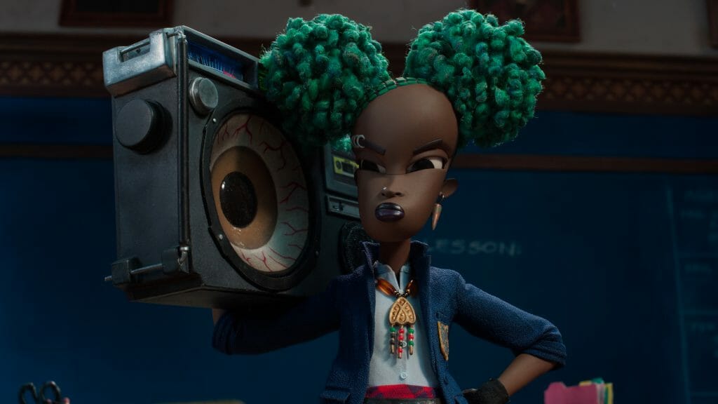 Kat the young Black goth girl holds a boom box painted to look like a huge eye ball in front of her classroom in the Netflix stop motion animation film WENDELL & WILD.
