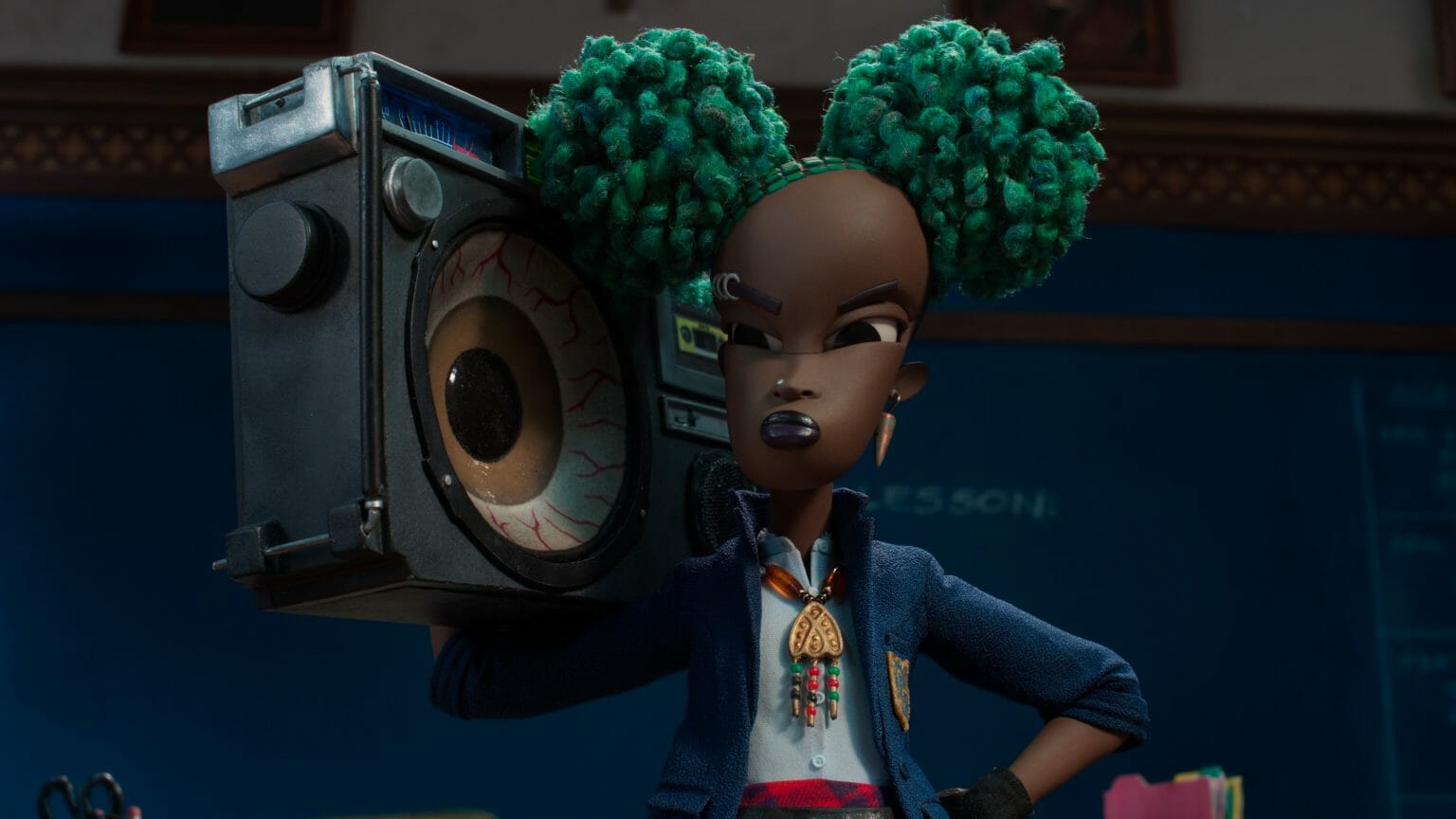 Kat the young Black goth girl holds a boom box painted to look like a huge eye ball in front of her classroom in the Netflix stop motion animation film WENDELL & WILD.