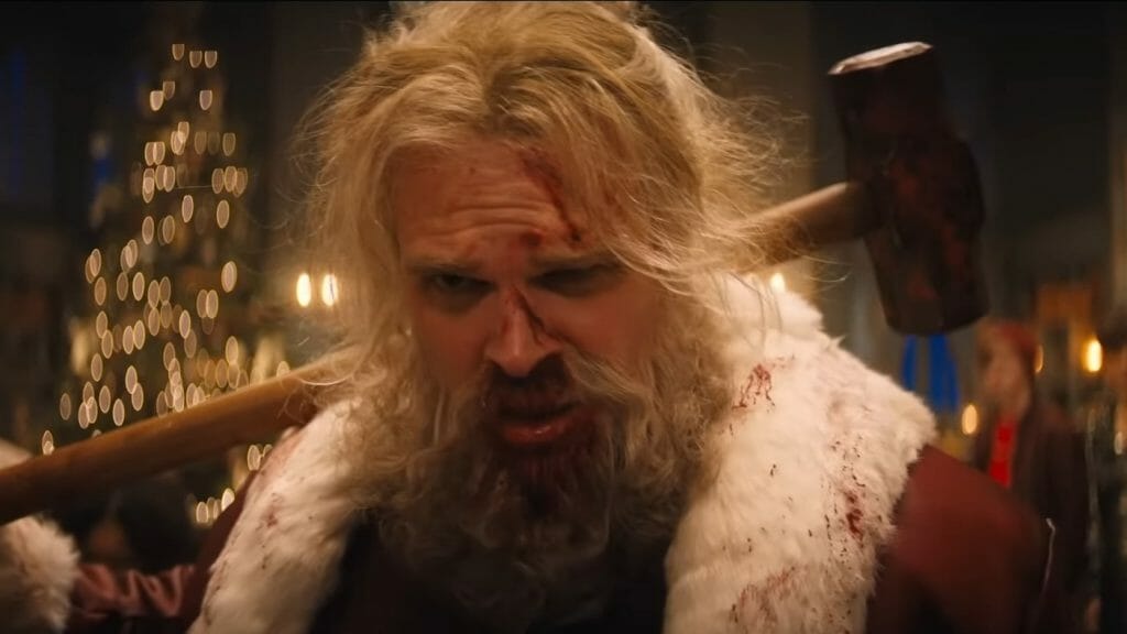 David Harbour as Santa Claus stands tired of combat with his bloody sledge hammer over his shoulder in the action Christmas comedy VIOLENT NIGHT.