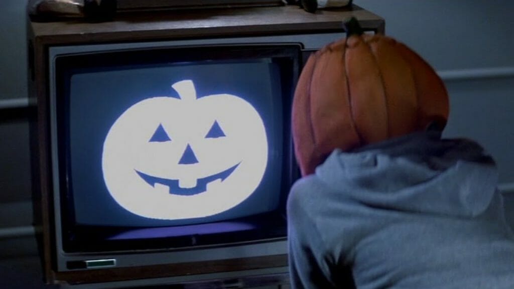 A young boy wearing a pumpkin mask watches the Silver Shamrock commercial from HALLOWEEN III: SEASON OF THE WITCH. 