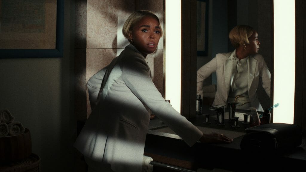 Janelle Monáe as Andi Brand stands frozen in fear while searching for clues in a bathroom during a power outage in GLASS ONION: A KNIVES OUT MYSTERY on Netflix. 