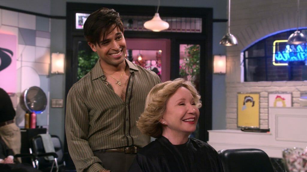 Wilmer Valderrama as Fez styles the hair of Kitty played by Debra Jo Rupp in his new styling salon in Point Place Wisconsin in the spin-off series That '90s Show on Netflix.