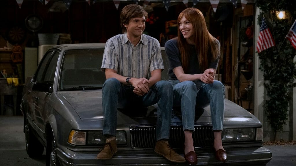 Topher Grace as Eric Forman and Laura Prepon as Donna Pinciotti reunite and sit on top of the roof of their car like old times in the reboot series That '90s Show on Netflix. 