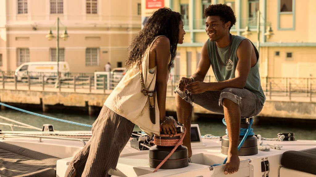 Carlacia Grant as Cleo and Jonathan Daviss as Pope act flirtatious on a boat in OUTER BANKS Season 3 on Netflix.
