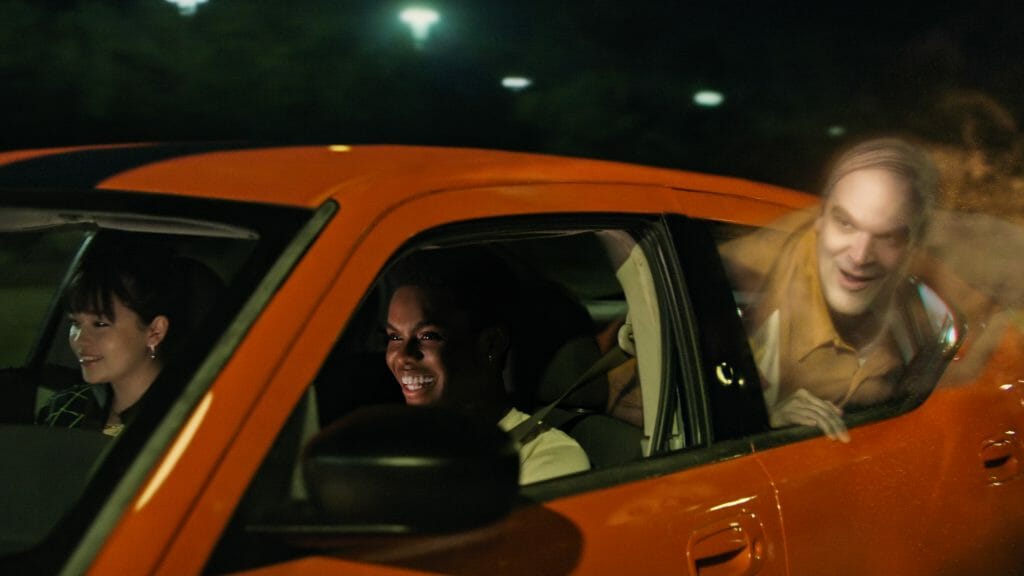 David Harbour as Ernest the silent ghost sticks out his head from the window while riding in the backseat of a fast red car with Isabella Russo and Jahi Winston sitting in the front in the Netflix original film WE HAVE A GHOST. 