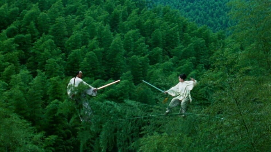 The legendary warrior Li Mu Bai played by Chow Yun-Fat and a governor's daughter Jen Yu played by Zhang Ziyi engage in a flying sword fight high in the trees of a green forest in CROUCHING TIGER, HIDDEN DRAGON directed by Ang Lee.